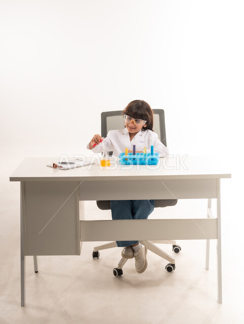 A dream to become a chemical researcher, choosing and determining a future career since childhood, conducting experiments and biochemical reactions in the laboratory, portrait of an Arab Gulf Omani girl wearing a white coat and using test tubes, a Saudi girl conducting scientific research in a chemistry laboratory, white background