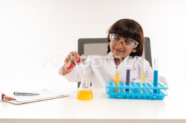 A dream to become a chemical researcher, choosing and determining a future career since childhood, conducting experiments and biochemical reactions in the laboratory, portrait of an Arab Gulf Omani girl wearing a white coat and using test tubes, a Saudi girl conducting scientific research in a chemistry laboratory, white background