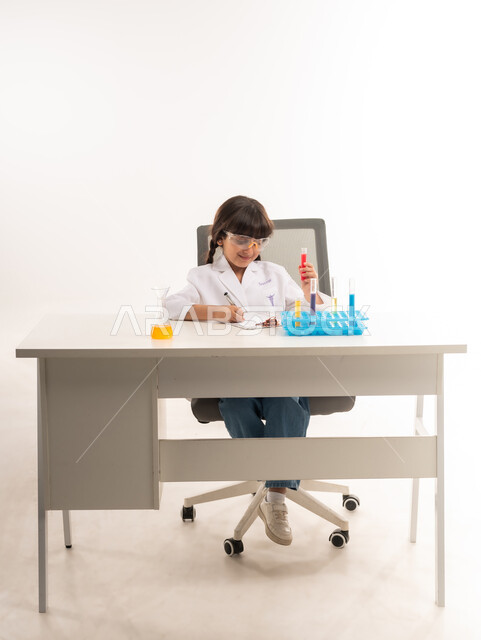 اجراء تجارب وتفاعلات كيميائيه حيويه في المختبر، بورتريه لفتاة عربية خليجية عمانية ترتدي معطف أبيض وتستخدم انابيب الاختبار، بنت سعودية تقوم بأبحاث علمية في معمل الكيمياء، أمنية الحصول على مهنة الباحثة الكيميائية، اختيار وتحديد المهنة المستقبلية منذ الصغر، خلفية بيضاء