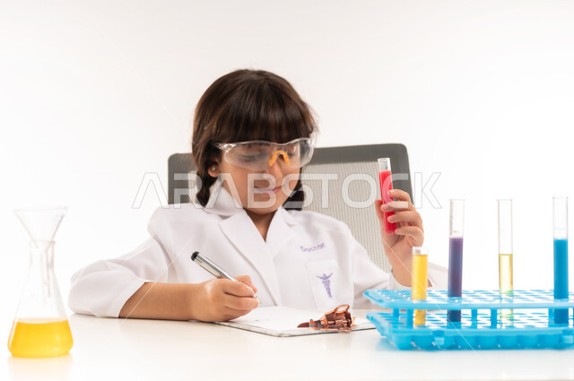 اجراء تجارب وتفاعلات كيميائيه حيويه في المختبر، بورتريه لفتاة عربية خليجية عمانية ترتدي معطف أبيض وتستخدم انابيب الاختبار، بنت سعودية تقوم بأبحاث علمية في معمل الكيمياء، أمنية الحصول على مهنة الباحثة الكيميائية، اختيار وتحديد المهنة المستقبلية منذ الصغر، خلفية بيضاء