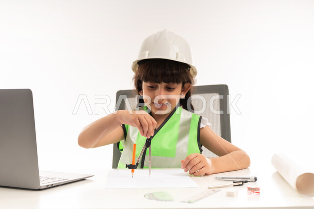 اختيار المستقبل منذ الصغر، العمل في القطاع الهندسي في سلطنة عمان، استخدام الاجهزة التقنية الحديثة في القطاع الهندسي، بنت سعودية بايماءات الشغف لتحقيق حلم الطفولة، بورتريه لفتاة عربية  خليجية عمانية ترتدي الستره تجلس امام الطاولة تستخدم الحاسوب المحمول، حلفية بيضاء