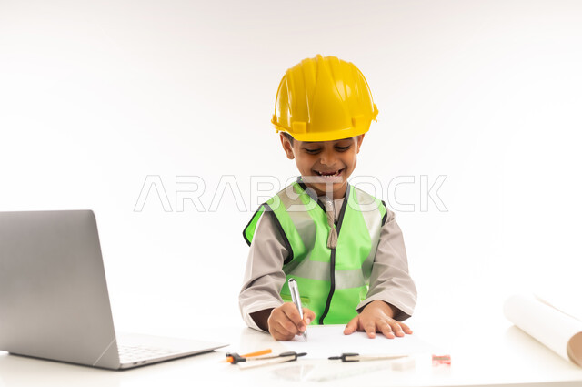 تحديد واختيار المستقبل منذ الصغر، العمل في القطاع الهندسي في سلطنة عمان، استخدام الاجهزة التقنية الحديثة في القطاع الهندسي، ايماءات الشغف لتحقيق حلم الطفولة، بورتريه لولد عربي خليجي عماني يرتدي الدشداشة والستره يجلس امام الطاولة يستخدم الحاسوب المحمول، حلفية بيضاء