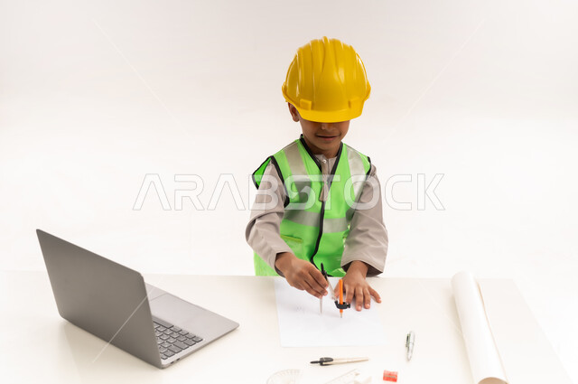 Working in the engineering sector in the Sultanate of Oman, using modern technical devices in the engineering sector, gestures of passion to achieve a childhood dream, portrait of an Arab Gulf Omani boy wearing a dishdasha and a jacket sitting in front of a table using a laptop, choosing and determining the future from a young age, white cloak