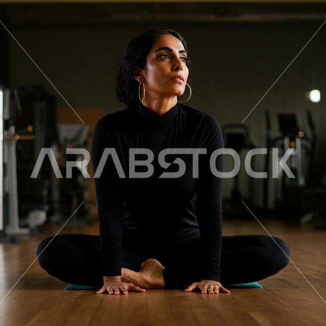 Practicing yoga, enhancing endurance and patience, following a healthy lifestyle, maintaining health and physical fitness, a young Saudi Arabian Gulf woman wearing sportswear and doing meditation and relaxation exercises, going to the gym on a regular basis