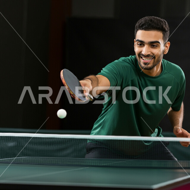  الاستمتاع بالمباريات الودية والبطولات المحلية، ممارسة رياضات وأنشطة بدنية ممتعة، شاب عربي خليجي سعودي يرتدي ملابس رياضية يحمل بيده مضرب تنس الطاولة، اللعب بسرعة وتركيز عالي، المحافظة على الرشاقة واللياقة الجسدية