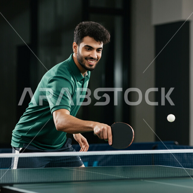  الاستمتاع بالمباريات الودية والبطولات المحلية، ممارسة رياضات وأنشطة بدنية ممتعة، شاب عربي خليجي سعودي يرتدي ملابس رياضية يحمل بيده مضرب تنس الطاولة، اللعب بسرعة وتركيز عالي، المحافظة على الرشاقة واللياقة الجسدية