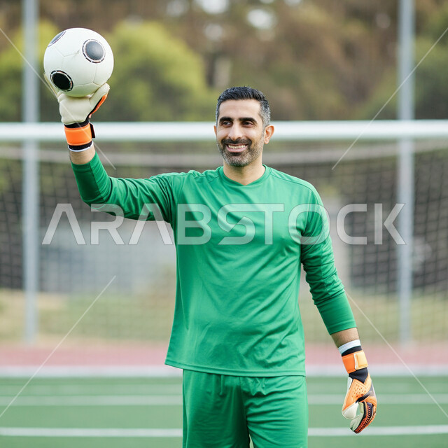 Professionalism in blocking strong shots, participation in international competitions, interest in the Saudi Arabian Football League, a Saudi Arabian Gulf Arab goalkeeper wearing sportswear and gloves holding the ball and looking at the camera with gestures of happiness, holding friendly matches
