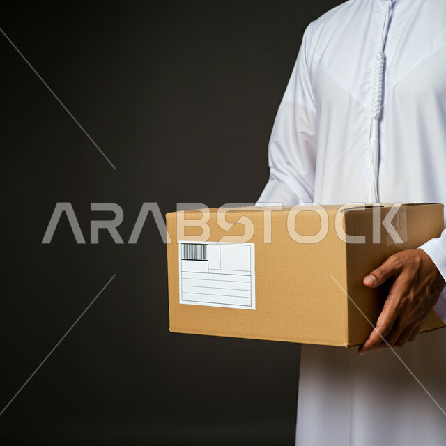 Ordering products online, e-shopping concept, express delivery services, relying on online purchases, close-up portrait of an Emirati Gulf Arab man wearing a kandura holding a box in his hands, delivering orders to customers easily and quickly, black background