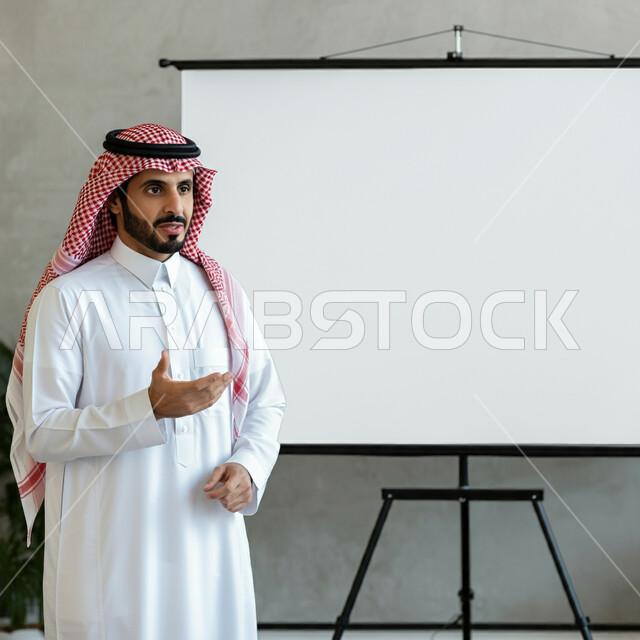 المقررات والمناهج التعليمية الحديثة والمطورة بالمملكة العربية السعودية، استخدام السبورة لسهولة الشرح، الاهتمام بقدرات الطلاب بتقديم الدروس, معلم عربي خليجي سعودي يرتدي الثوب التقليدي والشماغ يقوم بشرح الدروس