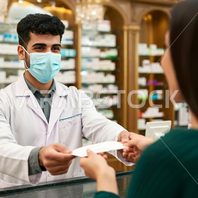 أداء الواجبات المهنية بجودة عالية، صرف العقاقير الموجودة في الوصفات الطبية ، توفير وتجهيز الادوية اللازمة للمريضة، استقبال المرضى وتقديم العلاج اللازم،  صيدلي عربي خليجي سعودي يرتدي الكمامة الطبية للوقاية من فايروس كورونا، مفهوم الصيدلة والرعاية الصحية