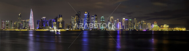 Waterfront on the coast of the Arabian Gulf, attracting and attracting people from all over the world, famous tourist places and landmarks, a panoramic image of the towers and skyscrapers lit at night in the city of Doha on the beach, progress and urban expansion in Qatar
