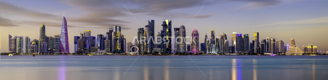 جذب و استقطاب السكان من كافة انحاء العالم، اماكن و معالم سياحية مشهورة، الواجهة البحرية على ساحل الخليج العربي، صورة بانورامية للابراج وناطحات السحاب المضاءة ليلا في مدينة الدوحة على الشاطئ، التقدم والتوسع العمراني في قطر