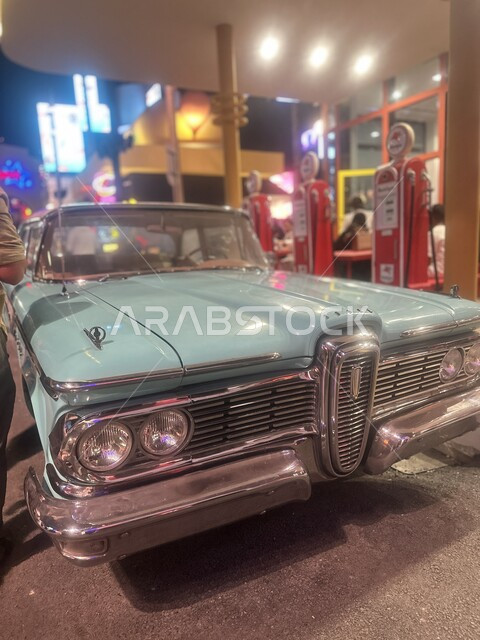 سيارة زرقاء كلاسيكية بجانب مبنى الألعاب والترفيه في البوليفارد ورلد في مدينة الرياض، الاستمتاع بالتجارب الممتعة في أبرز المناطق الترفيهية بالمملكة العربية السعودية، اكتشاف الحضارات والثقافات حول العالم, معالم جذب واستقطاب السائحين