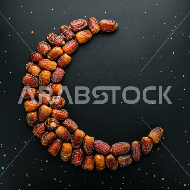زينة واجواء شهر رمضان المبارك، مجسم هلال مصنوع من حبات التمر السكري، تمور صحية لذيذة، وجبة ذات قيمة غذائية عالية الأهمية، منتجات ومحاصيل زراعية محلية وطنية، خلفية سوداء