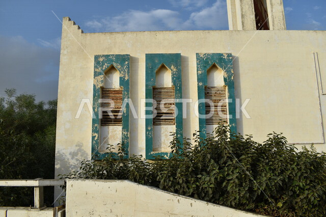صورة لنوافذ قديمة لمسجد قديم في منطقة الباحة محاط بمجموعة من الأشجار الخضراء ، معالم طبيعية و سياحية دينية في المملكة العربية السعودية 