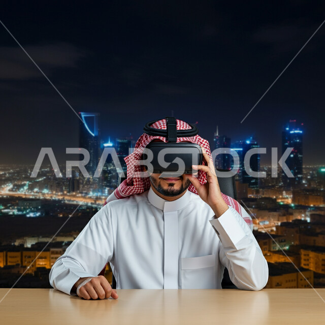 المتعة والتسلية بالمشاهدة عبر نظارة الواقع الافتراضي، رجل عربي خليجي سعودي يرتدي الثوب التقليدي والشماغ يجلس أمام مكتبه يضع نظارات ثلاثية الأبعاد، استخدام التقنية والاجهزة الحديثة، الإندماج ومحاكاة العالم الخيالي، خلفية الابراج وناطحات السحاب