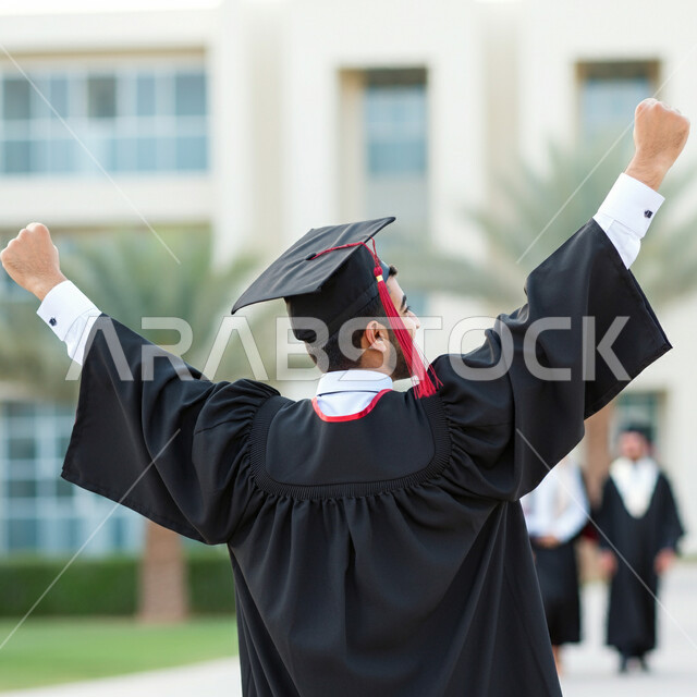 Expressions of success and victory, celebrating the completion of university studies, feeling proud and self-confident, the concept of diligence and excellence, a close-up image from the back of a Saudi Arabian Gulf student wearing an abaya and graduation cap raising his hands in victory gestures