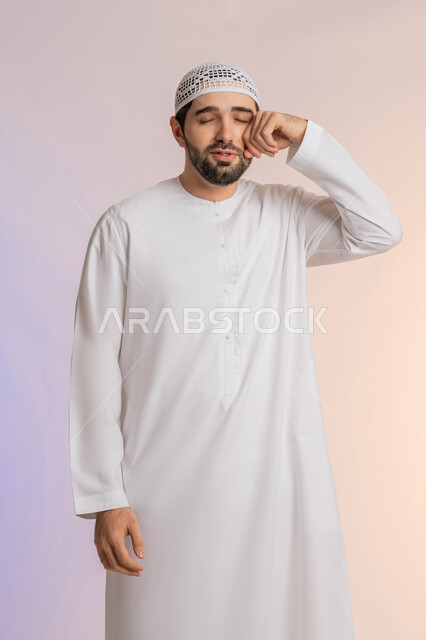 مشاكل التهاب اللثة وتسوس الأسنان, الاشارة إلى الفم بتعابير الإرهاق والتعب, بورتريه لرجل عربي خليجي اماراتي يرتدي الكندورة والقبعة ينظر الى الكاميرة بإيماءات الانزعاج والألم الشديد، خلفية ملونة