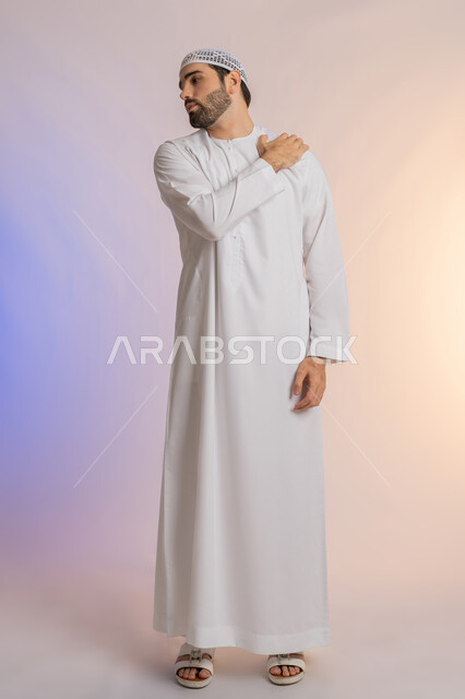 التهاب العضلات والمفاصل، الإحساس بالتعب والإرهاق, إيماءات الألم في الأكتاف، بورتريه من الخلف لرجل عربي خليجي اماراتي يرتدي الكندورة والقبعة البيضاء  يضع يده على كتفه بتعابير الوجع، الحاجه لوضع خطة علاجية, طلب المساعده للذهاب الى المستشفى، خلفية ملونة