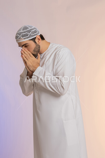 الشعور بالمرض و الزكام والحاجة الى العلاج والدواء, التهاب الأنف التحسسي,  بورتريه لشاب عربي خليجي اماراتي يرتدي الكندورة  والقبعة يضع يديه على وجهه بإيماءات العطاس, خلفية ملونة