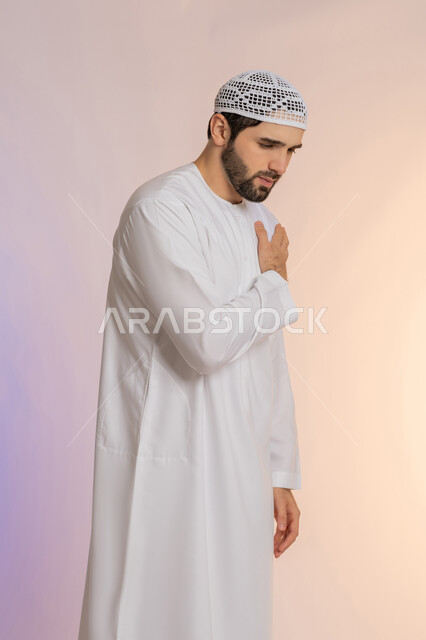 Feeling tired and exhausted, sore muscles and joints, gestures of pain in the shoulders, portrait of an Arab Gulf Emirati man wearing a kandura and a hat, placing his hand on his shoulder with an expression of pain, a colored background.