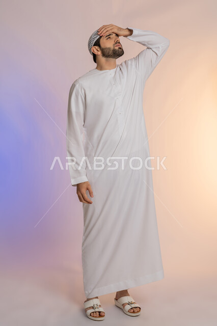 آلام الصداع النصفي، التعرض لنوبات الشقيقة الحادة, الحاجة لتناول المسكنات وأخذ قسط من الراحة، التعرض للتعب والإرهاق والعمل الطويل، بورتريه لرجل عربي خليجي اماراتي يرتدي الكندورة والقبعة يمسك رأسه بيديه بإيماءات الألم، الجسم بالطول الكامل خلفية ملونة
