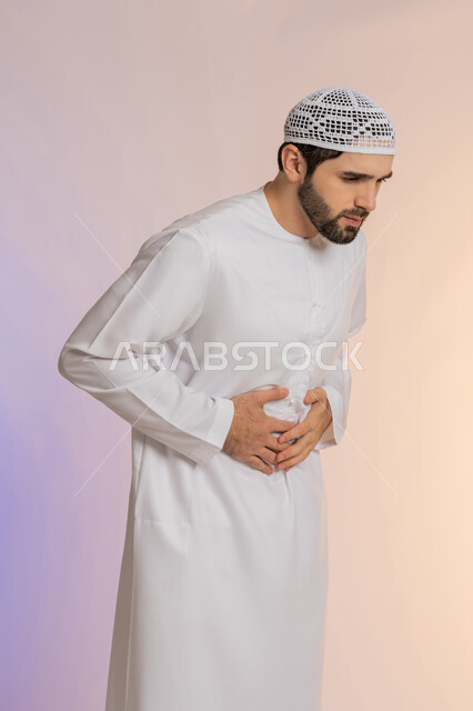 الإحساس بالمغص و التعب والإرهاق, عسر الهضم والشعور بحرقة في المعدة، الحاجة للدواء ووضع خطة علاجية, بورتريه لرجل عربي خليجي اماراتي يرتدي الكندورة والقبعة يمسك بطنه بإيماءات الألم، خلفية ملونة