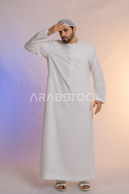 آلام الصداع النصفي، التعرض لنوبات الشقيقة الحادة, الحاجة لتناول المسكنات وأخذ قسط من الراحة، التعرض للتعب والإرهاق والعمل الطويل، بورتريه لرجل عربي خليجي اماراتي يرتدي الكندورة والقبعة يمسك رأسه بيديه بإيماءات الألم، الجسم بالطول الكامل خلفية ملونة