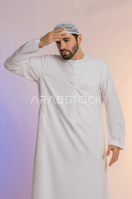 التعرض لنوبات الشقيقة الحادة، آلام الصداع النصفي،  الحاجة لتناول المسكنات وأخذ قسط من الراحة، التعرض للتعب والإرهاق والعمل الطويل، بورتريه لرجل عربي خليجي اماراتي يرتدي الكندورة والقبعة يمسك رأسه بيديه بإيماءات الألم، خلفية ملونة