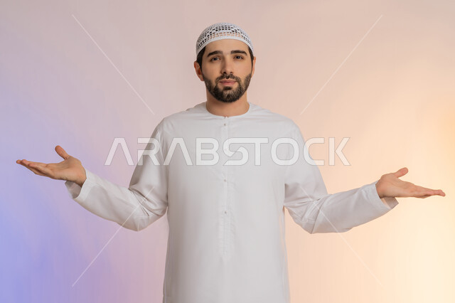 القلق والحيرة في اتخاذ القرار الصحيح، فتح اليدين في دلالة على الاستسلام، محاولة إيجاد حل للمشكلات العصبة، بورتريه لرجل عربي خليجي اماراتي  يرتدي الكندورة والقبعة ينظر إلى الكاميرا ويقف باستقامة، خلفية ملونة