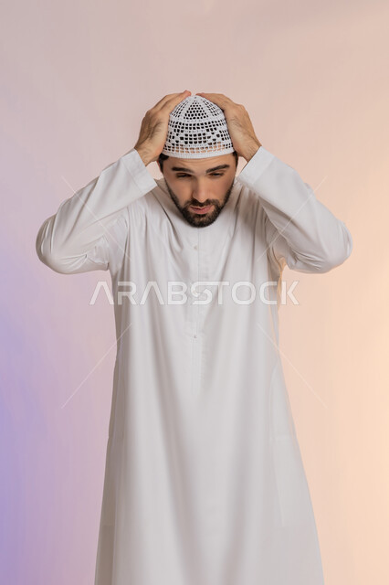 التعرض لنوبات الشقيقة الحادة، آلام الصداع النصفي،  الحاجة لتناول المسكنات وأخذ قسط من الراحة، التعرض للتعب والإرهاق والعمل الطويل، بورتريه لرجل عربي خليجي اماراتي يرتدي الكندورة والقبعة يمسك رأسه بيديه بإيماءات الألم، خلفية ملونة