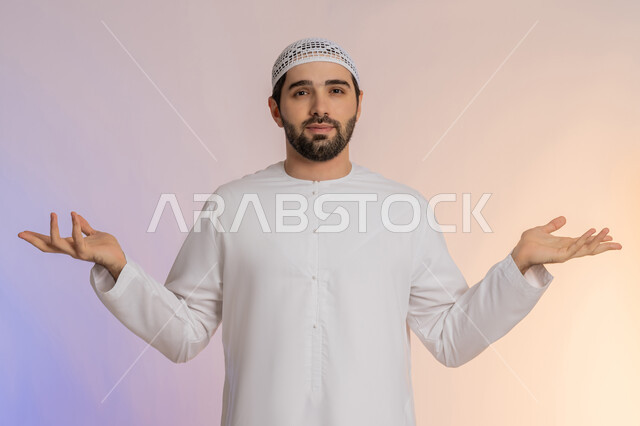 القلق والحيرة في اتخاذ القرار الصحيح، فتح اليدين في دلالة على الاستسلام، محاولة إيجاد حل للمشكلات العصبة، بورتريه لرجل عربي خليجي اماراتي  يرتدي الكندورة والقبعة ينظر إلى الكاميرا ويقف باستقامة، خلفية ملونة