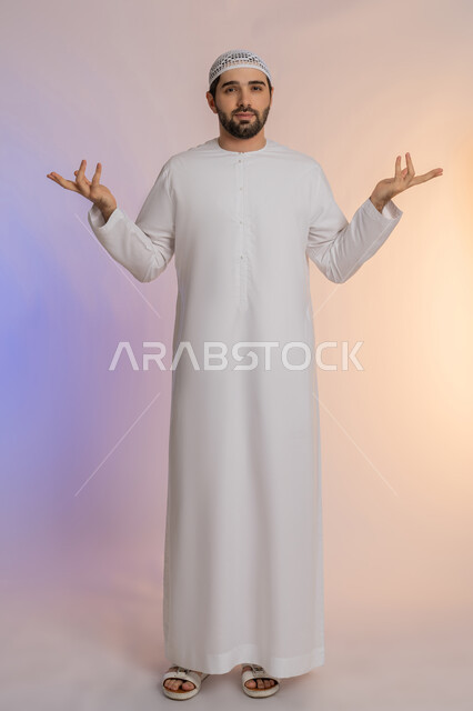 محاولة إيجاد حل للمشكلات العصبة، القلق والحيرة في اتخاذ القرار الصحيح، فتح اليدين في دلالة على الاستسلام، بورتريه لرجل عربي خليجي اماراتي  يرتدي الكندورة والقبعة ينظر إلى الكاميرة ويقف باستقامة، الجسم بالطول الكامل, خلفية ملونة
