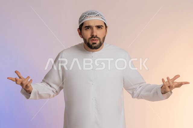 Trying to find a solution to difficult problems, anxiety and confusion in making the right decision, opening the hands as a sign of surrender, a portrait of an Arab Gulf Emirati man wearing a kandora and a hat, looking at the camera and standing straight, colored background.