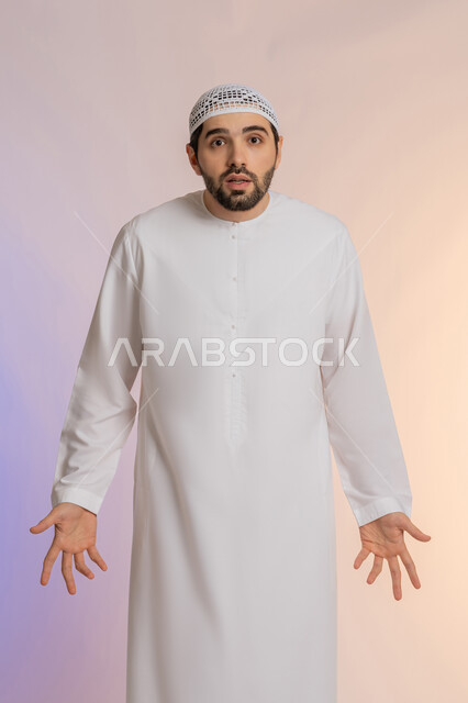 القلق والحيرة في اتخاذ القرار الصحيح، فتح اليدين في دلالة على الاستسلام، محاولة إيجاد حل للمشكلات العصبة، بورتريه لرجل عربي خليجي اماراتي  يرتدي الكندورة والقبعة ينظر إلى الكاميرا ويقف باستقامة، خلفية ملونة