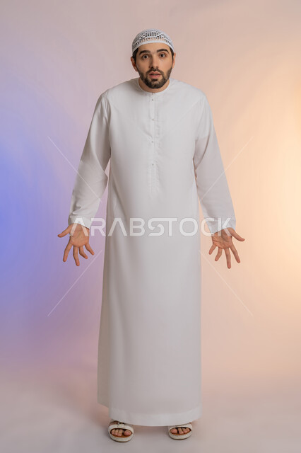 فتح اليدين في دلالة على الاستسلام، القلق والحيرة في اتخاذ القرار الصحيح، محاولة إيجاد حل للمشكلات العصبة، بورتريه لرجل عربي خليجي اماراتي  يرتدي الكندورة والقبعة ينظر إلى الكاميرا ويقف باستقامة، الجسم بالطول الكامل، خلفية ملونة