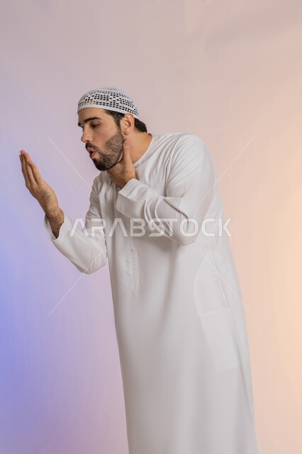 الاحساس بألم البلعوم, الحاجة إلى العلاج والدواء, مفهوم الاهتمام بالصحة, الاصابة بنزلة برد والتهاب الحلق, بورتريه لرجل عربي خليجي اماراتي يرتدي الكندورة والقبعة البيضاء يضع يديه على حلقه ويشعر بالاختناق, خلفية ملونة