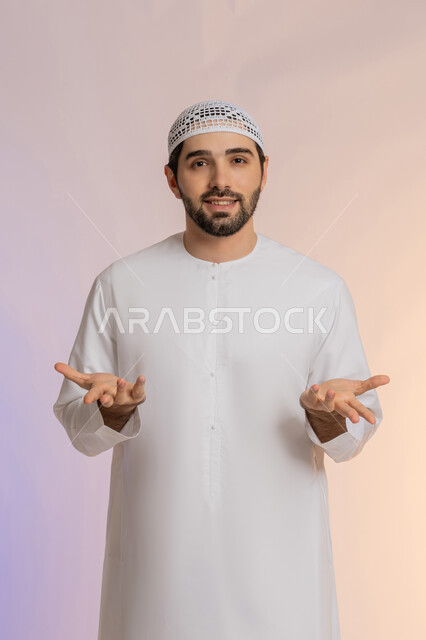 التفاجؤ والاستغراب من شيء ما، الوقوف بإيماءات التعجب والدهشة، الشعور بالسعادة والسرور لسماع الأخبار المنتظرة، بورتريه لرجل عربي خليجي اماراتي يرتدي الكندورة والقبعة يفتح يديه بتعابير الصدمة والذهول والانبهار، خلفية ملونة