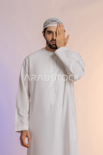التهاب واحمرار العيون والحاجة لزيارة الطبيب، وضع اليد على العين وتغطيها، ضعف النظر وتشوش الرؤية، بورتريه لرجل عربي خليجي اماراتي يرتدي الكندورة والقبعة يعاني من مشاكل صحية في عينه، خلفية ملونة