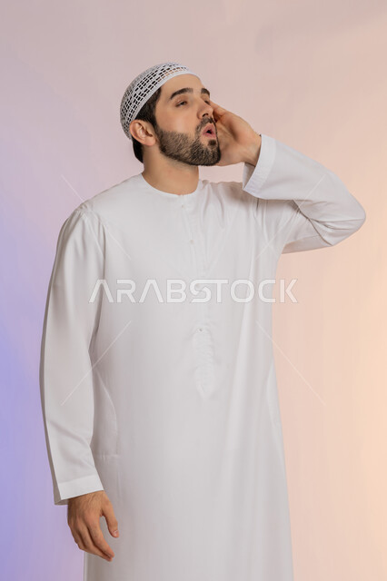 النداء بصوت مرتفع, الصراخ والتكلم بنبرة عالية للسماع بشكل جيد، وضع اليد بجانب الفم لزيادة حدة الأصوات، بورتريه لرجل عربي خليجي اماراتي يرتدي الكندورة والقبعة  ينظر إلى مكان ما بإيماءات الاندماج,  خلفية ملونة
