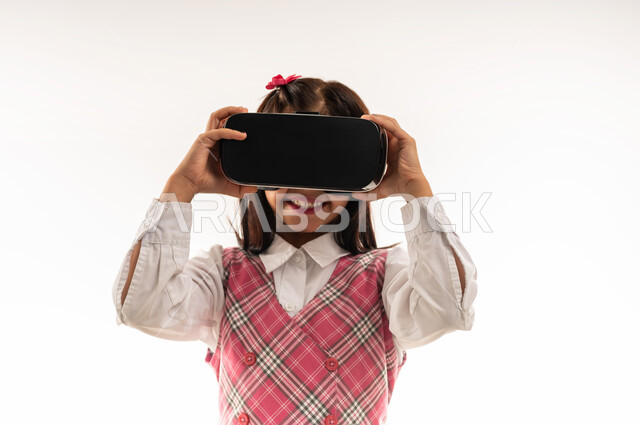 Development of teaching methods using modern advanced technologies, close-up portrait of an Arab Gulf Omani girl wearing a school uniform and wearing 3D virtual reality glasses, a Saudi schoolgirl looking at something with gestures of integration and concentration, white background