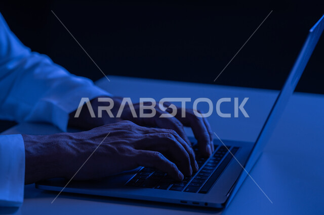 A young Saudi man with fast typing skills on the keyboard, a close-up of the hands of an Arab Gulf Emirati man working on a laptop, administrative office tasks and jobs, data entry and typing through the keyboard, integrating work with technology and technology
