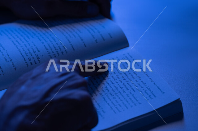 مفهوم الثقافة والتعلم الذاتي, شاب سعودي يقوم بقراءة القصص والروايات الممتعة, صورة مقربة لأيدي رجل عربي خليجي إماراتي يرتدي الكندورة يقوم بتتبع الكتابة في الكتاب، تنمية الذخيرة الثقافية، قضاء أوقات الفراغ بممارسة هواية المطالعة