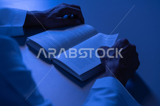 مفهوم الثقافة والتعلم الذاتي, شاب سعودي يقوم بقراءة القصص والروايات الممتعة, صورة مقربة لأيدي رجل عربي خليجي إماراتي يرتدي الكندورة يمسك بيده الكتاب, تنمية الذخيرة الثقافية، قضاء أوقات الفراغ بممارسة هواية المطالعة