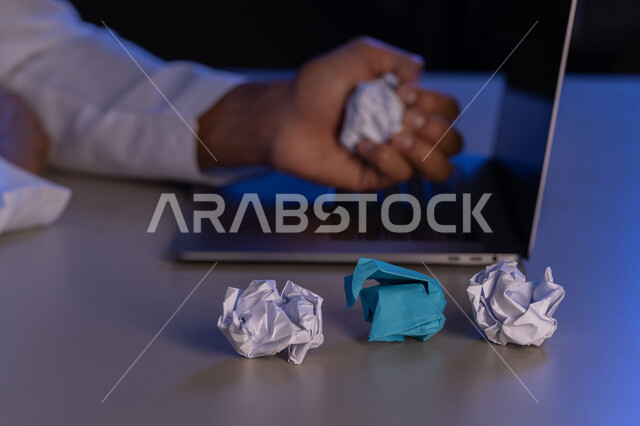 الفشل في العمل، صورة مقربة لرجل عربي خليجي اماراتي يرتدي الكندورة وبجانبه مجموعة من الاوراق المجعدة ، شاب سعودي يبحث عن افكار وخطط، الاخفاق في الكتابة والتدوين ، محاولة ايجاد حلول لتاليف قصة