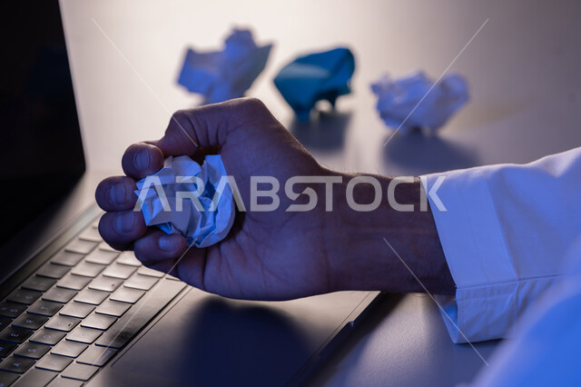 الفشل في العمل، صورة مقربة لرجل عربي خليجي اماراتي يرتدي الكندورة وبجانبه مجموعة من الاوراق المجعدة ، شاب سعودي يبحث عن افكار وخطط، الاخفاق في الكتابة والتدوين ، محاولة ايجاد حلول لتاليف قصة