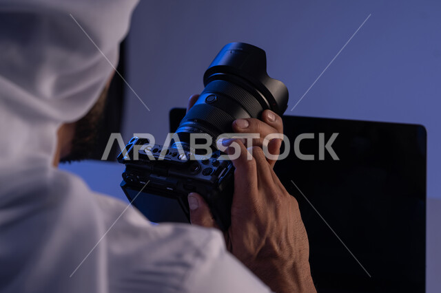 إتقان واحتراف مهنة التصوير، تعلم أخذ لقطات تذكارية فنية، ممارسة الهواية المفضلة بشغف، صورة مقربة من الخلف لرجل عربي خليجي اماراتي يعمل على جهاز الحاسوب المحمول وبجانبه كاميرا فوتوغرافية، استخدام التقنيات الحديثة المتطورة، شاب سعودي يقوم بتعديل جلسة التصوير