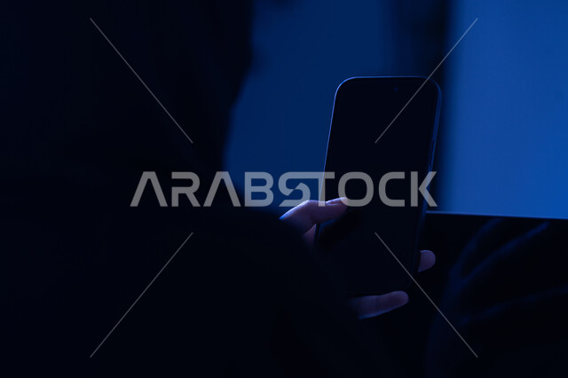 عرض شاشة سوداء فارغة، استخدام الاجهزة التقنية الحديثة، صورة مقربة من الخلف لامرأة عربية خليجية اماراتية تحمل بيدها الهاتف المحمول، شابة سعودية تقوم بالعمل على جهاز اللابتوب، التسويق والترويج للمواقع الالكترونية