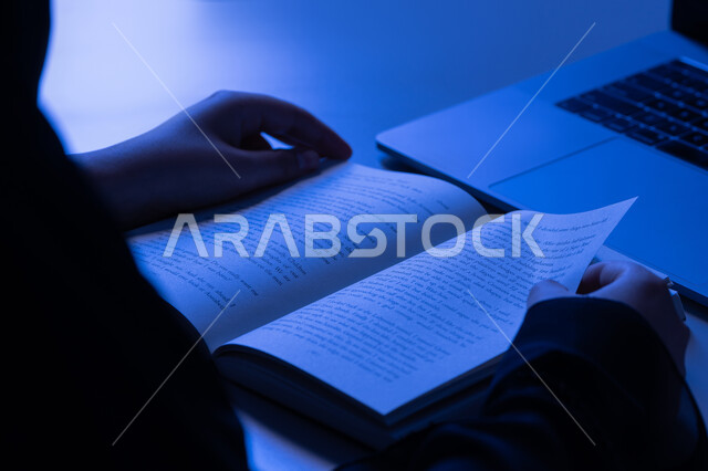 مفهوم الثقافة والتعلم الذاتي, الاستمتاع بالأنشطة الترفيهية المفيدة في وقت الفراغ، شابة سعودية تقوم بقراءة القصص والروايات الممتعة, صورة مقربة لأيدي امرأة عربية خليجية اماراتية ترتدي العباءة تقوم بممارسة هواية المطالعة