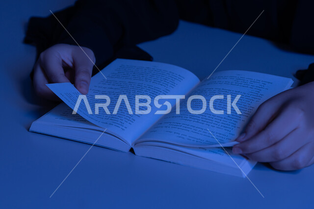 مفهوم الثقافة والتعلم الذاتي, الاستمتاع بالأنشطة الترفيهية المفيدة في وقت الفراغ، شابة سعودية تقوم بقراءة القصص والروايات الممتعة, صورة مقربة لأيدي امرأة عربية خليجية اماراتية ترتدي العباءة تقوم بممارسة هواية المطالعة